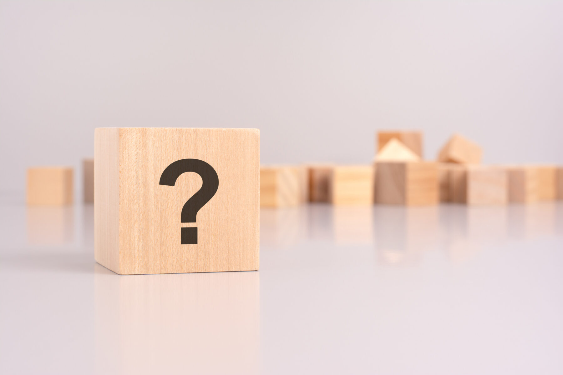 wooden cube with question mark over a grey background with copy space